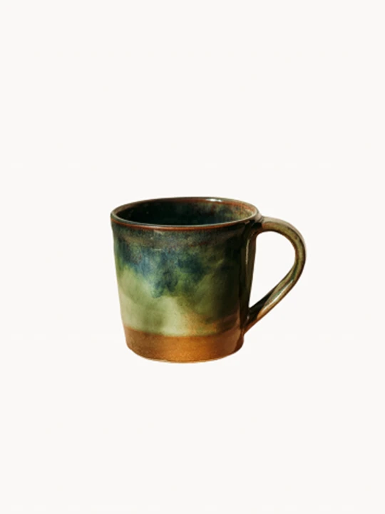 A ceramic mug with a rustic design, featuring a smooth glaze in shades earthy green that fade into a natural brown base, on a plain white background.